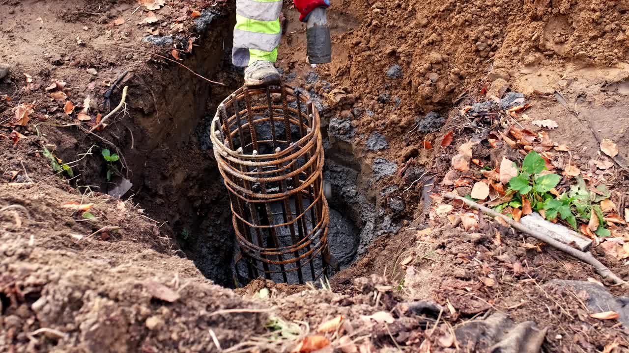 建筑工人从管道填充混凝土基础挖掘用钢筋笼浇注液体水泥视频素材