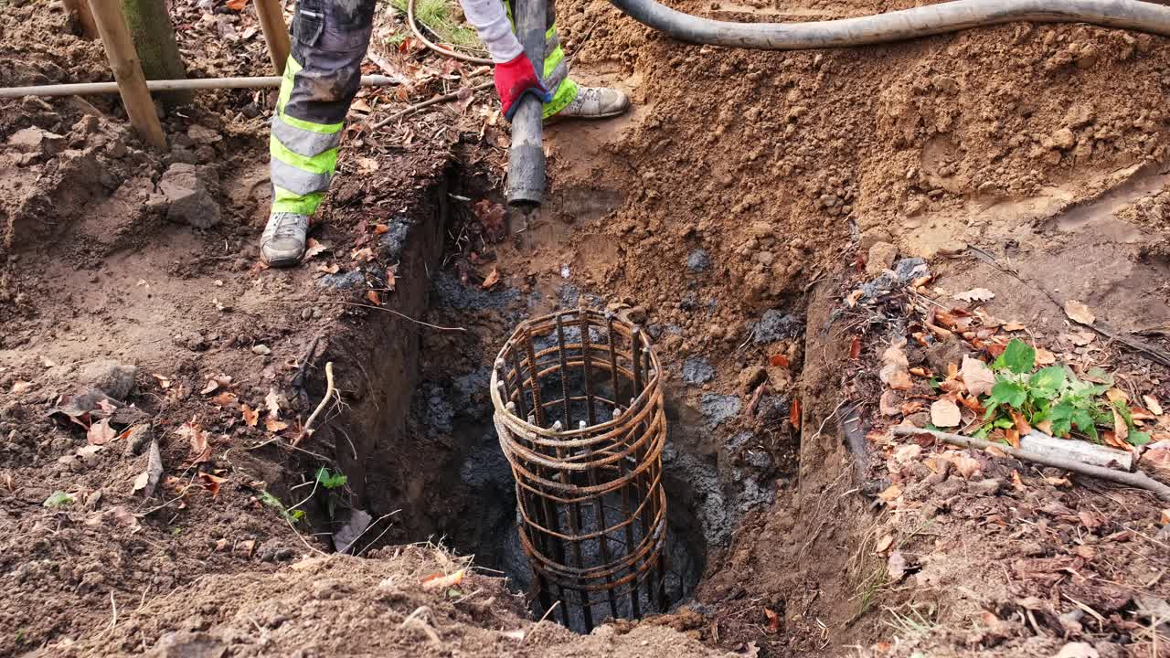 建筑工人从管道填充混凝土基础挖掘用钢筋笼浇注液体水泥视频素材