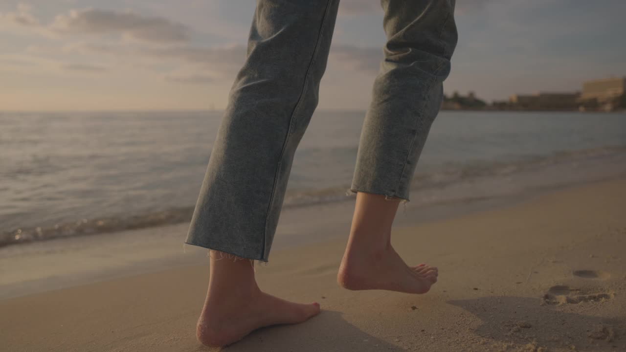 光着脚的女人在沙滩上行走的背影视频素材