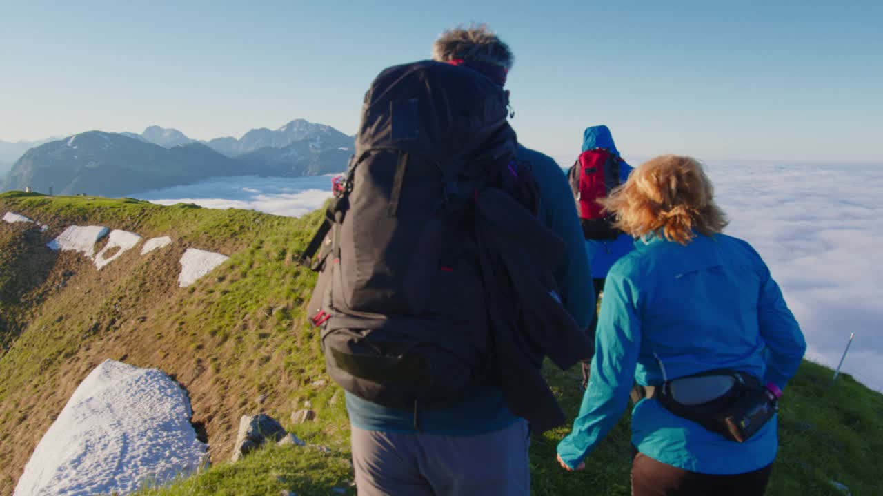 三个徒步旅行者在山脊上行走视频素材