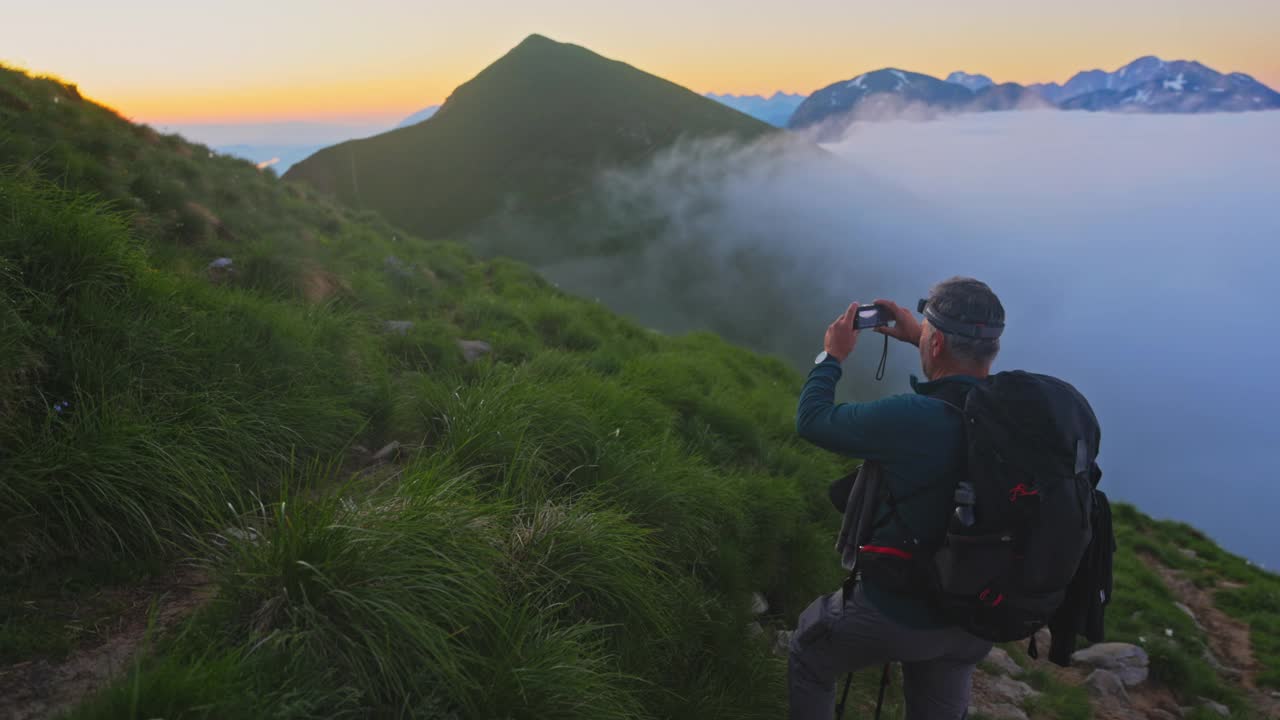 一个徒步旅行者在山坡上的草地上拍照视频素材