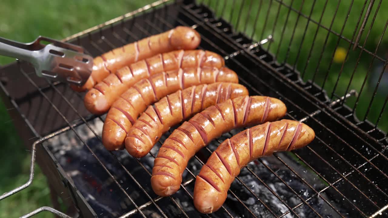 在烟熏中烹煮香肠。野餐时用木炭烤的美味食物。厨师在烤架上烤牛肉热狗香肠。特写镜头。视频素材