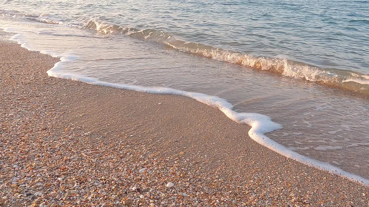 在夕阳的照耀下，海浪翻滚到海滩上，慢动作。视频素材