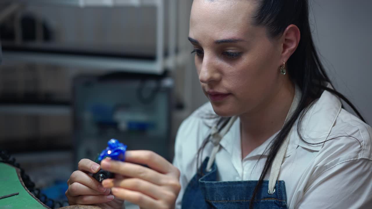 年轻的集中女珠宝商与设备在室内的车间。白人妇女肖像与工具制作手工配件在慢动作。工艺和风格的概念。视频素材