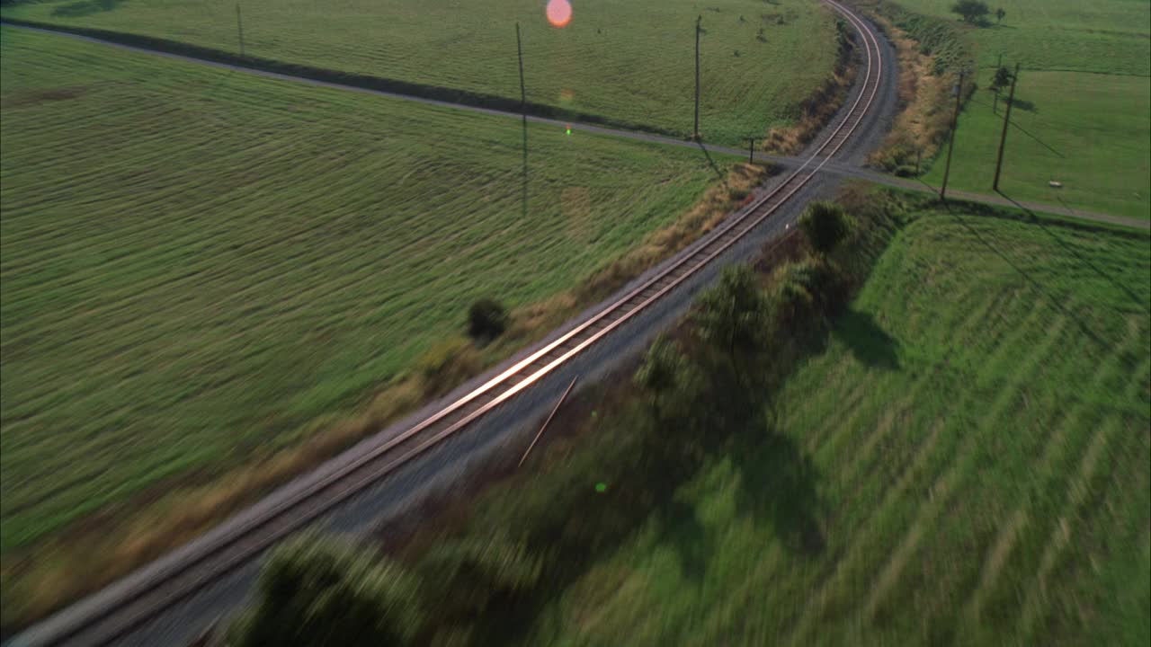 在乡村地区或被草地包围的乡村的铁路或铁路的空中轨道。视频素材