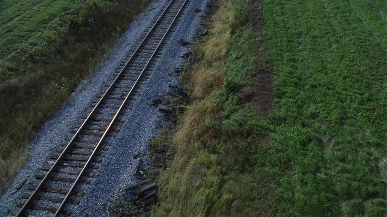 在乡村地区或被草地包围的乡村的铁路或铁路的空中轨道。视频素材