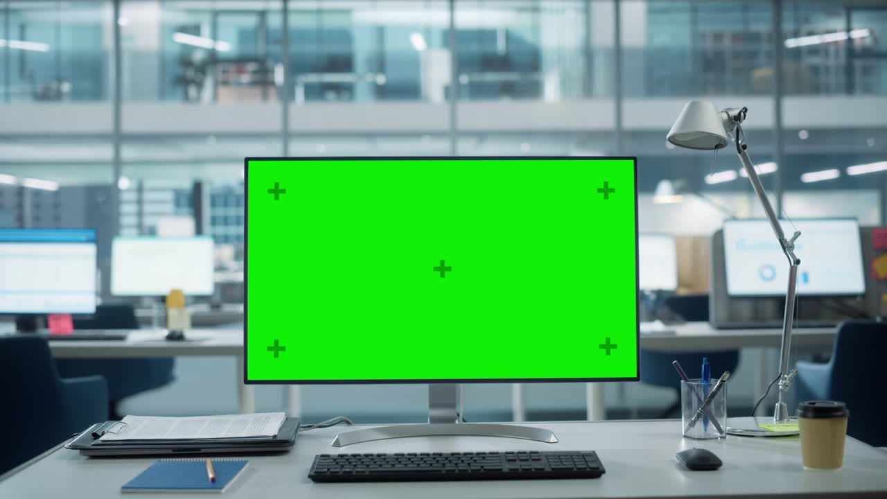 台式机显示器与模拟绿屏Chroma键显示站在桌上的现代商务办公室。背景玻璃墙与大城市办公室。放大照片。视频素材