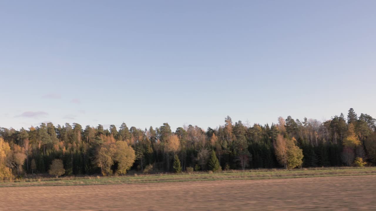 美丽的秋日和车上的风景。美丽的风景有田野，森林树木和蓝天白云。瑞典。视频素材