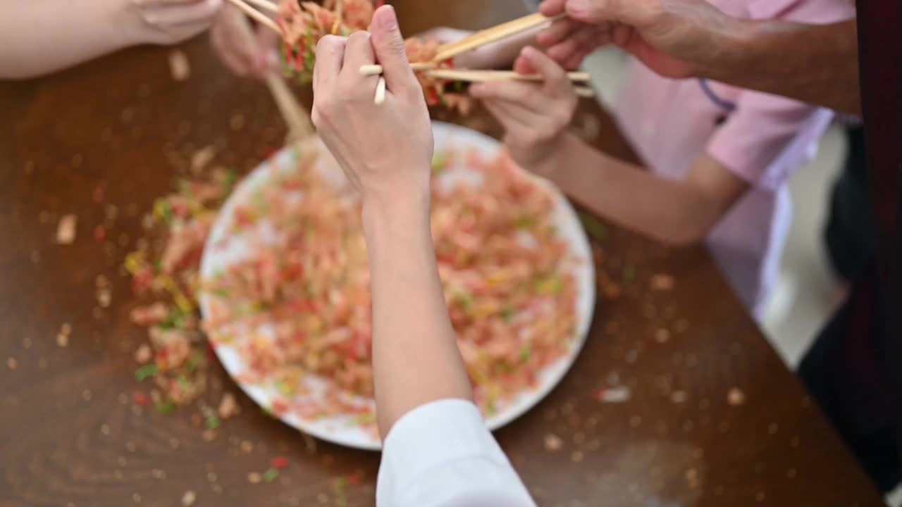 一个亚洲家庭在团圆饭上用传统食物“生鱼”庆祝中国新年视频素材