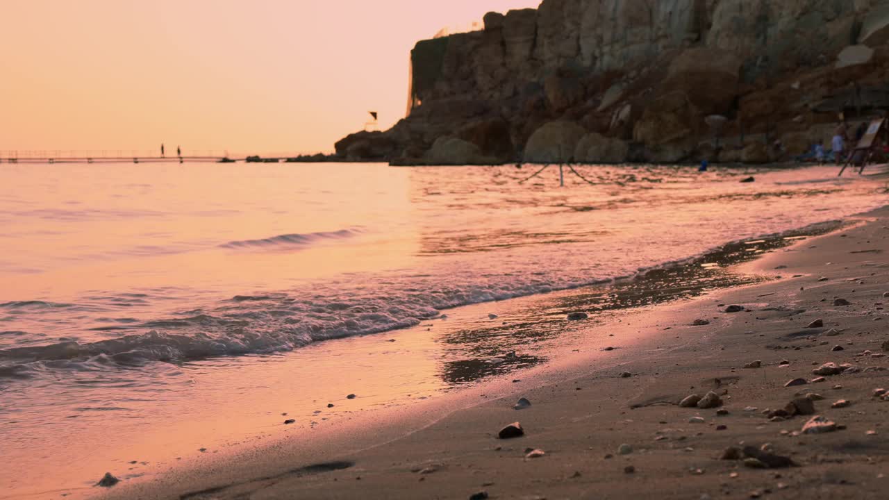 女孩在美丽的日落中漫步在海滩上。在宁静的夏夜，女人沿着海岸线漫步视频素材