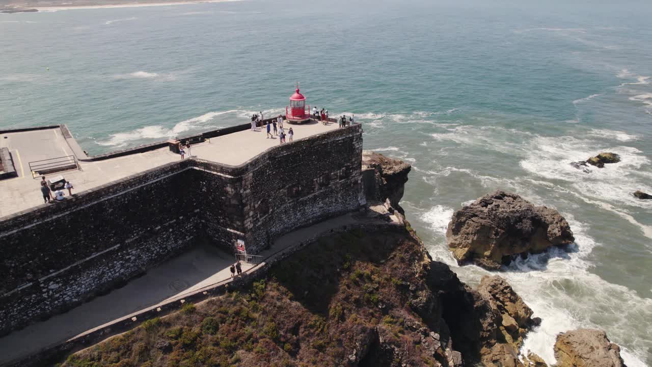 鸟瞰以海景为背景探索Nazaré灯塔的游客视频素材