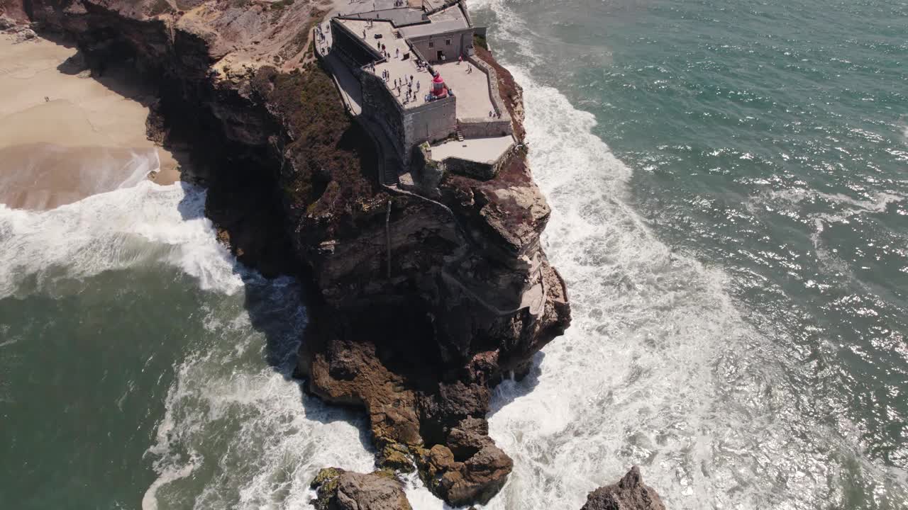 海浪在纳扎雷灯塔和葡萄牙大天使圣米迦勒城堡的悬崖上冲刷视频素材