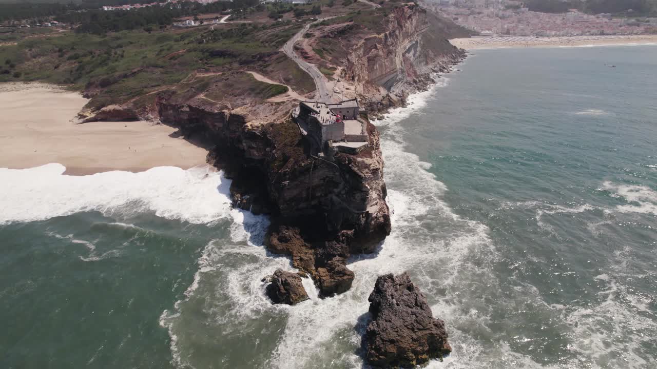 海浪冲击着岩石峭壁，顶部是大天使圣迈克尔堡垒和纳扎雷灯塔。视频素材