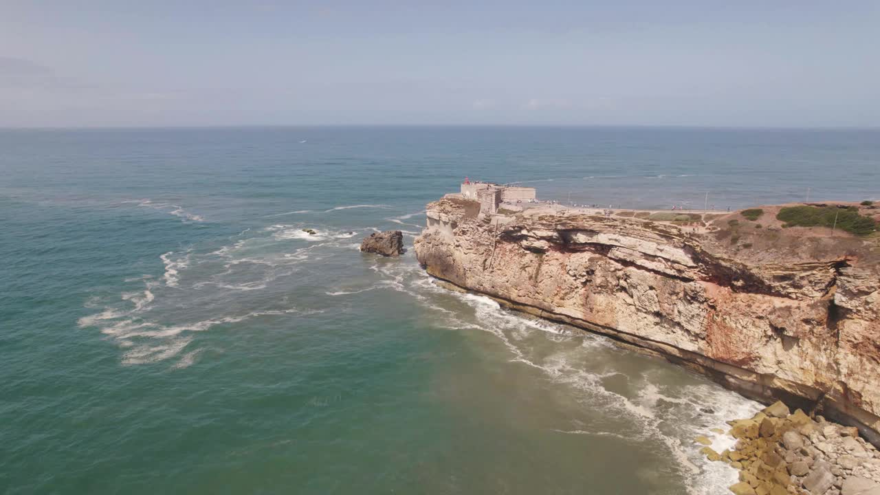 空中飞向悬崖上的灯塔堡垒，田园诗般的海洋色彩- Nazaré视频素材