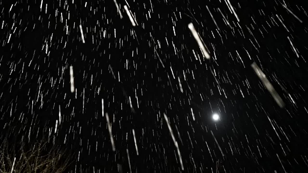 晚上暴风雪。狂风大作的降雪迅速向相机移动。在暴风雪中向前移动。黑色背景。雪花飘落，纹理斑驳。镜头。冬天的季节。视频素材