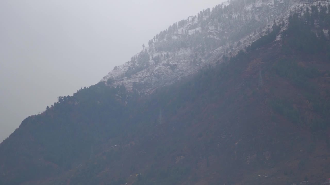 在喜马偕尔邦的马纳里，冬天被雪覆盖的山顶，印度。在冬季，山顶被雪和雾所覆盖。视频素材