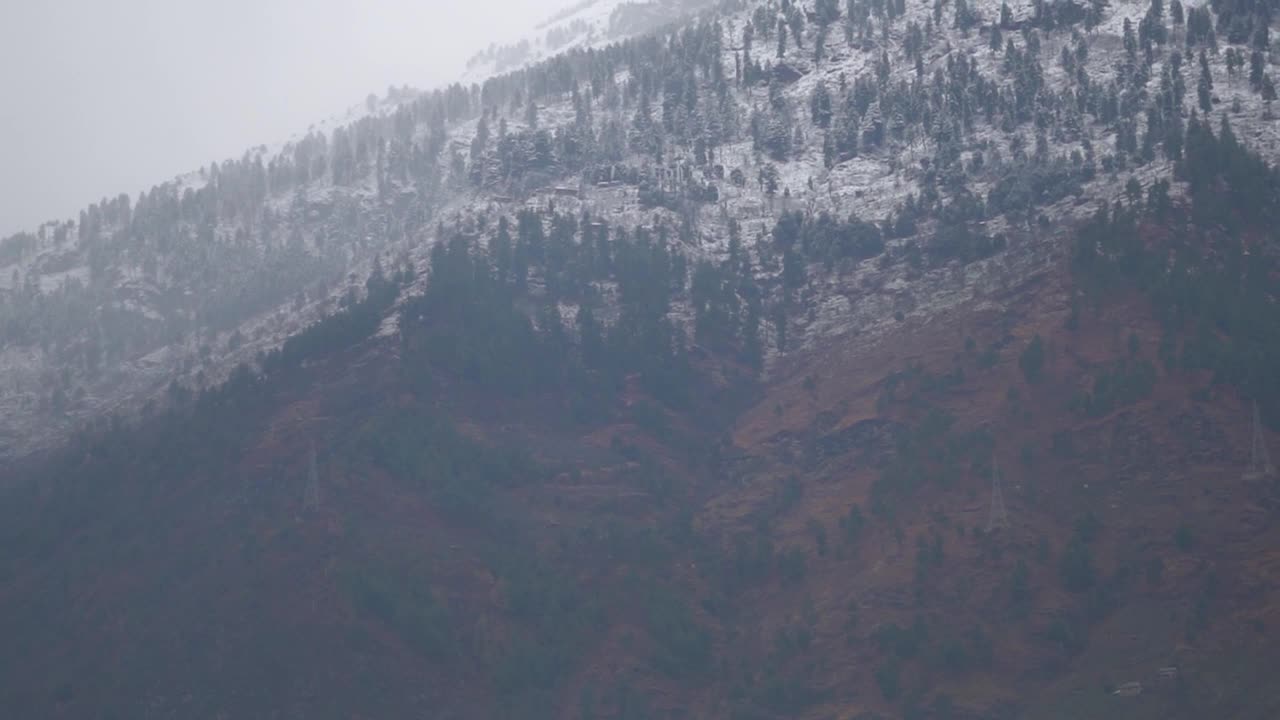 在喜马偕尔邦的马纳里，冬天被雪覆盖的山顶，印度。在冬季，山顶被雪和雾所覆盖。视频素材