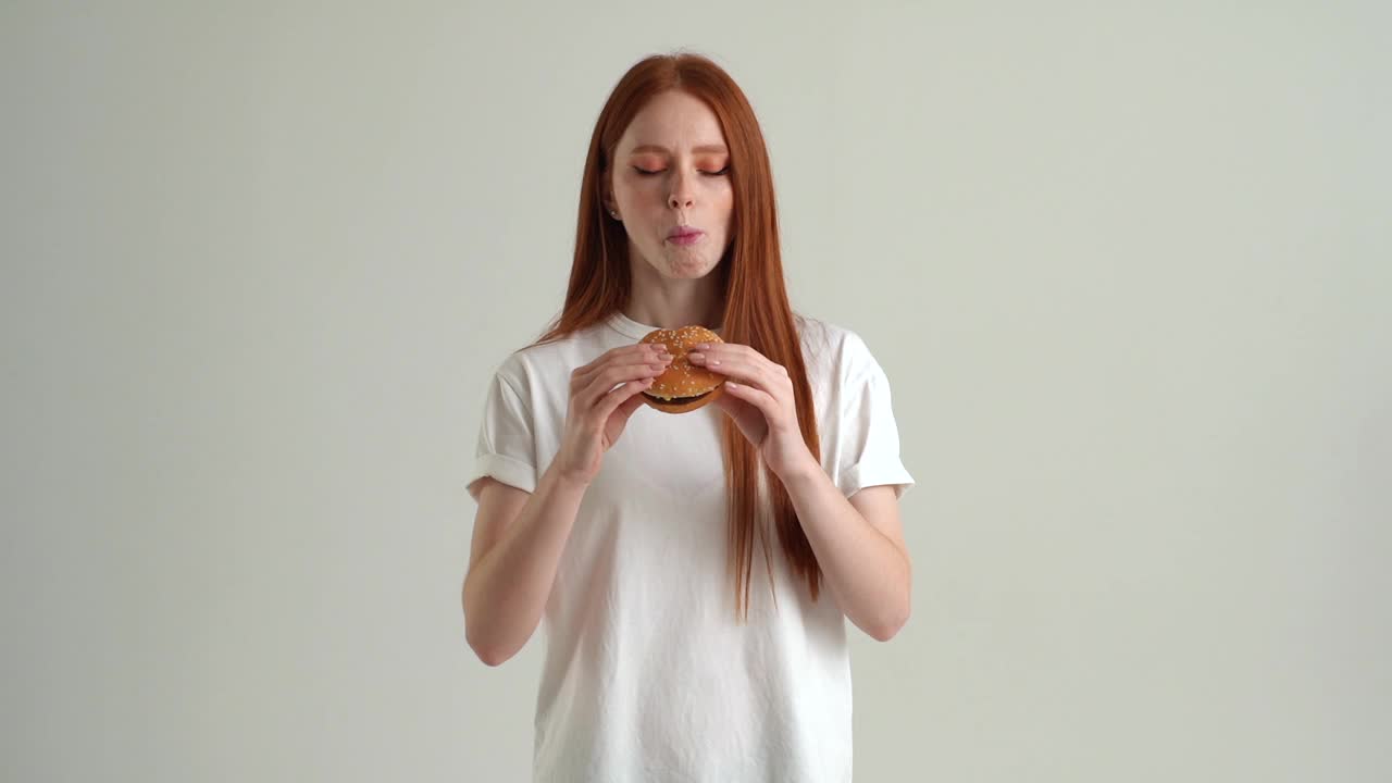 饥饿的年轻女子吃汉堡，胃疼，恶心，食物中毒症状，胃炎。视频素材