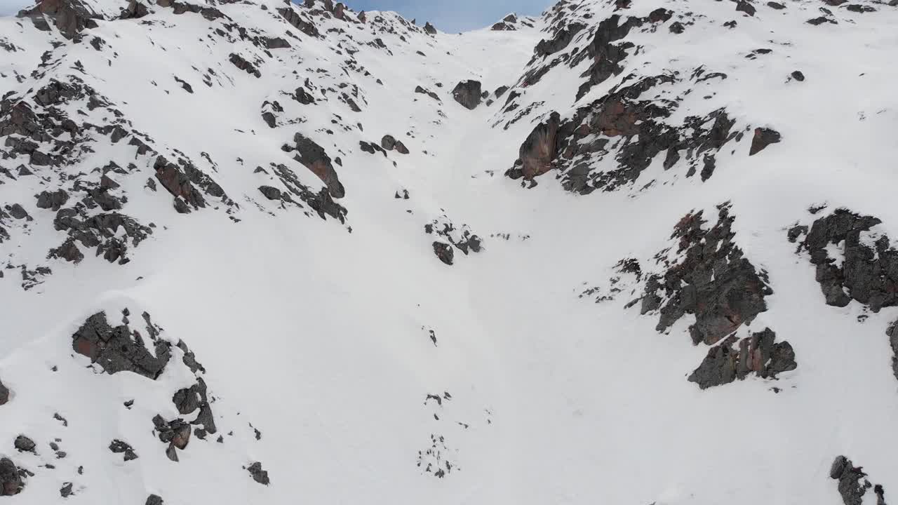 高山中冰雪覆盖的岩石斜坡。陡峭的颜色适合极限滑雪。高级骑手的免费乘车点。鸟瞰图视频素材