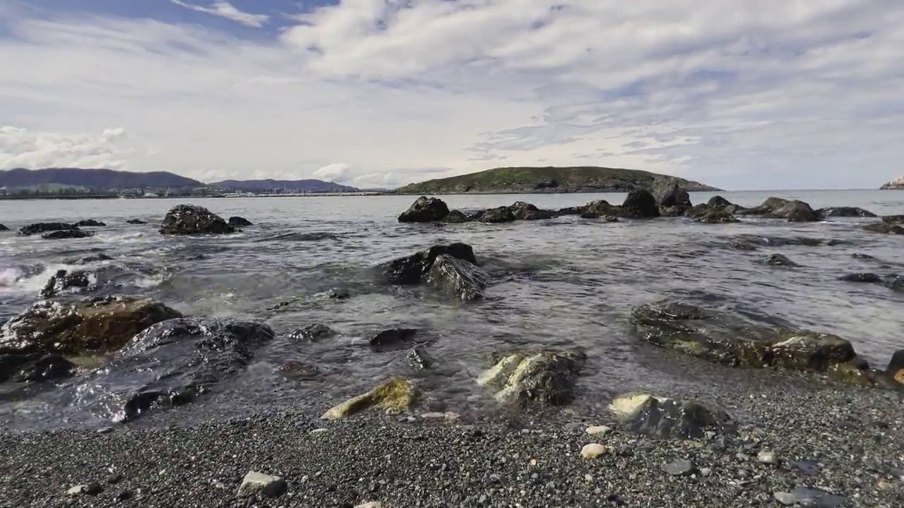 海浪在黑色的沙滩和岩石海岸线上。视频素材