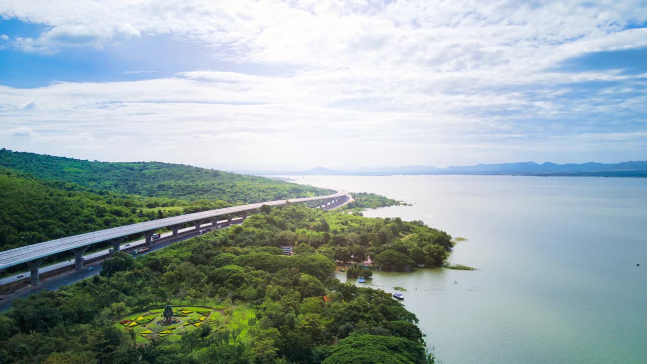 空中无人机超延时延时美丽的高速公路在绿色森林与大坝在公路的一边之间的山。视频素材