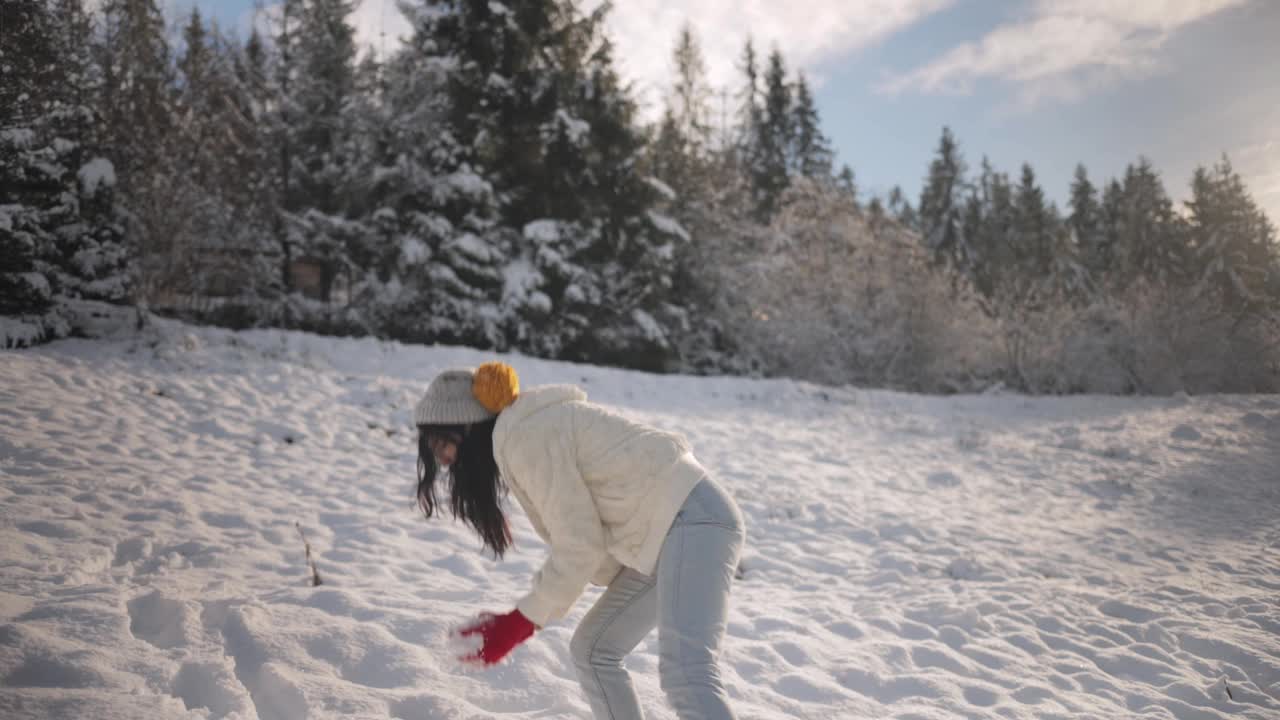 女子玩冬季游戏，在山林户外扔雪球视频素材