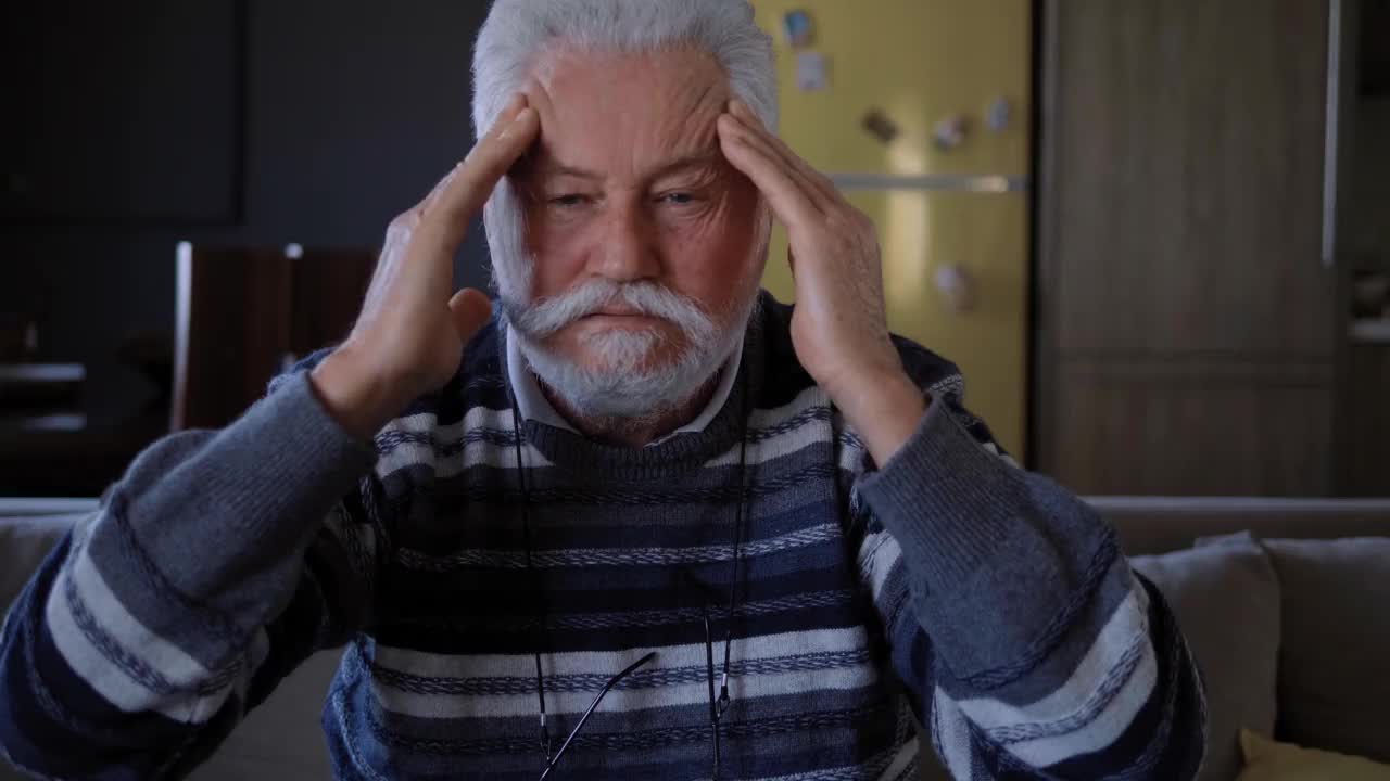 一位老人揉了揉头，看着镜头。头痛和头部健康问题。老年男子患偏头痛视频素材