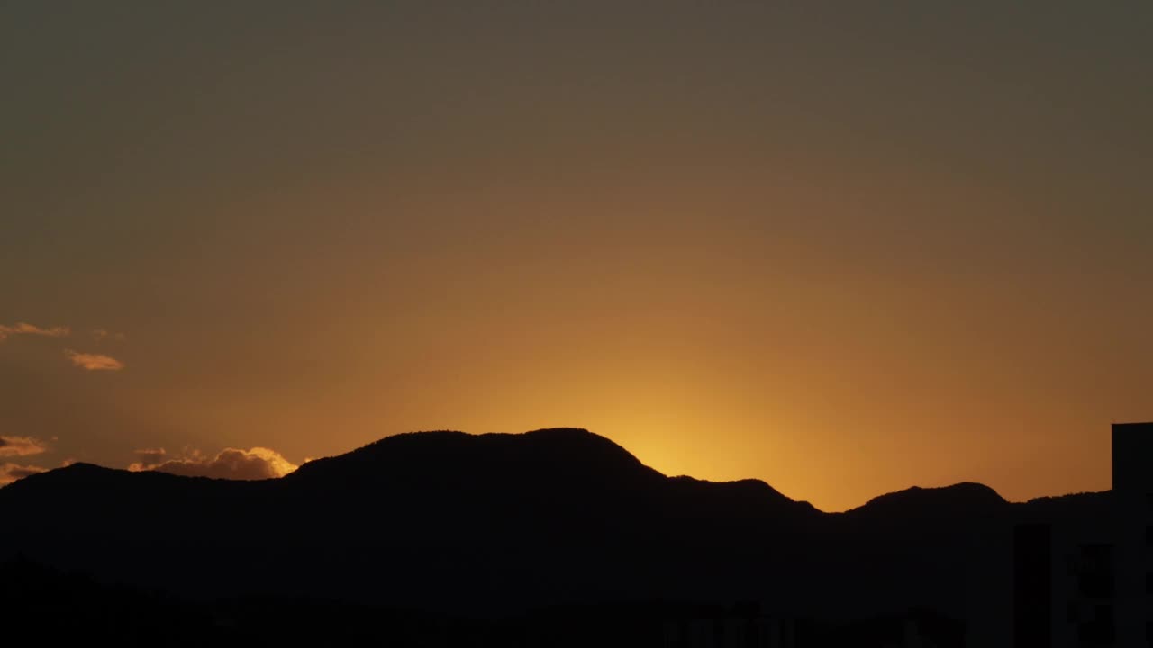 从白天到夜晚，夕阳西下，橘黄色的天空勾勒出群山的轮廓视频素材