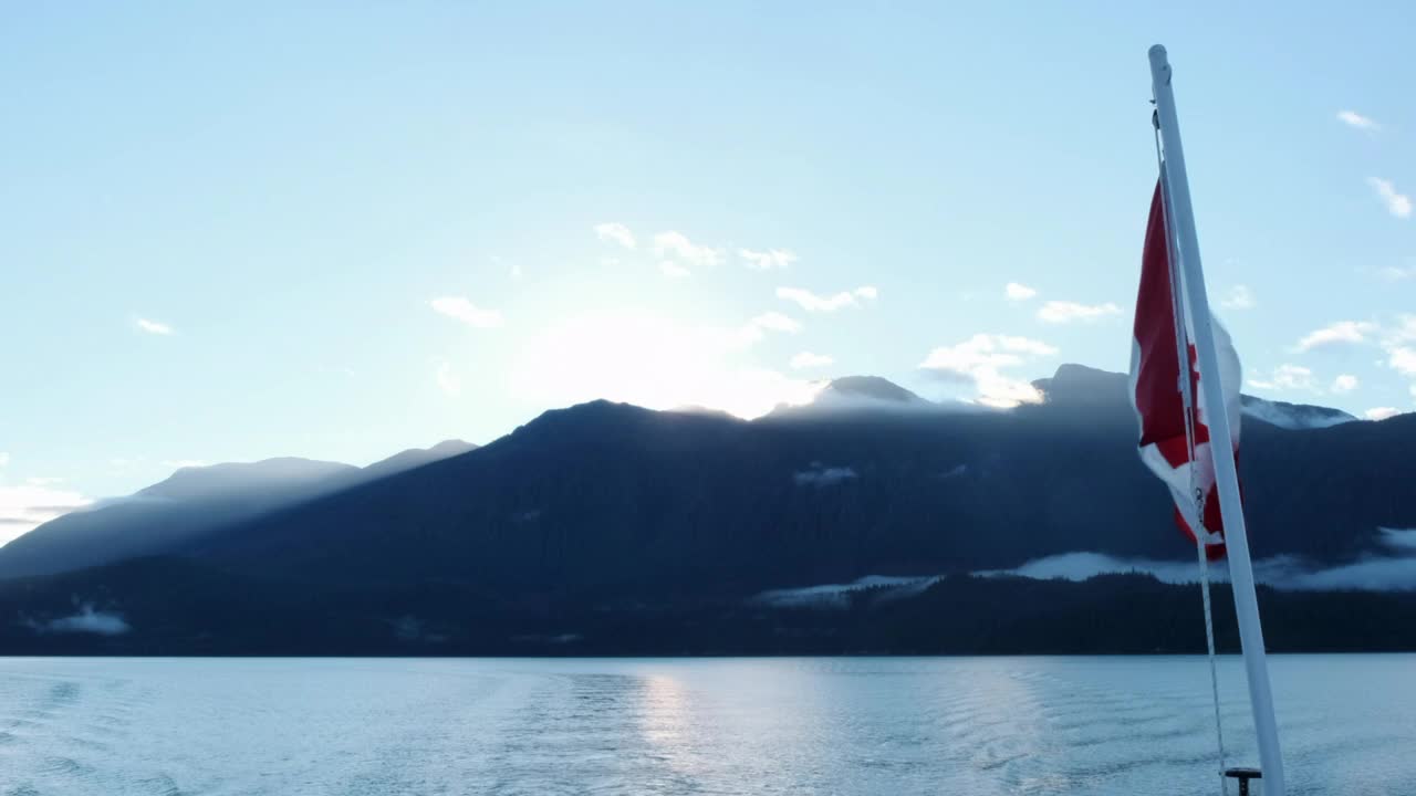 太阳从山上升起，船上挂着加拿大国旗视频素材