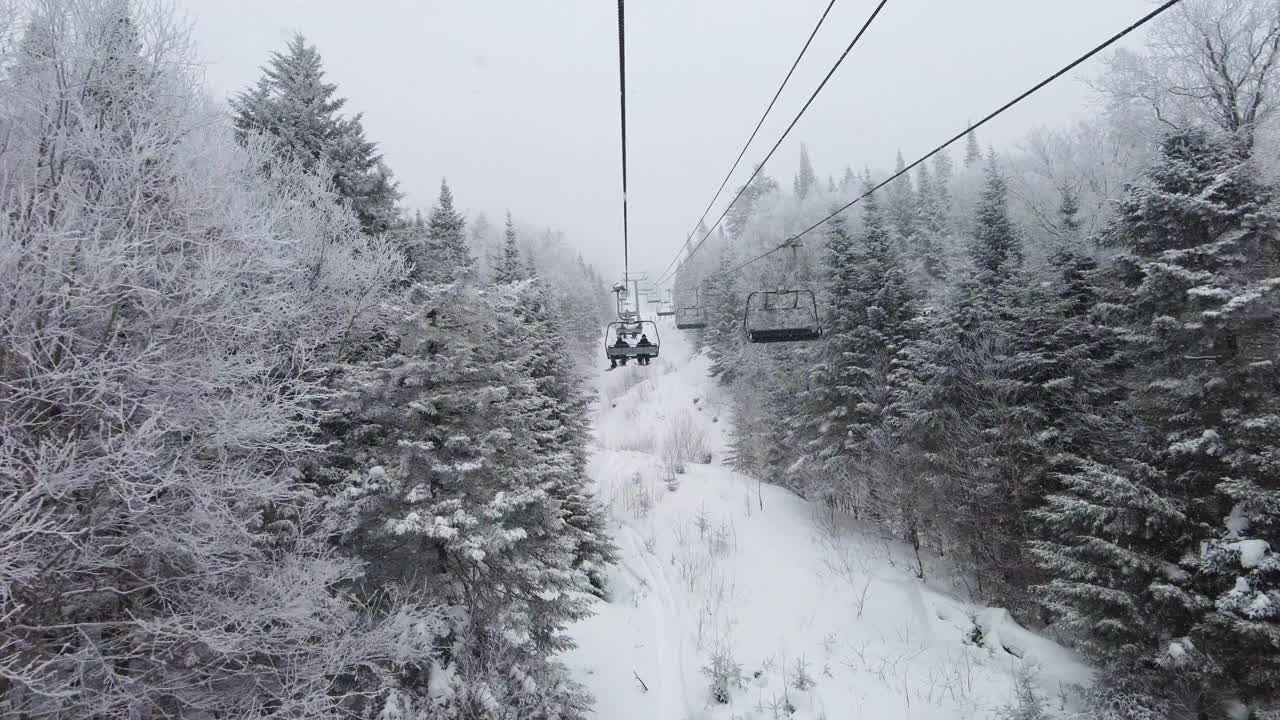 滑雪缆车在田园诗般的冬季景观与雪和树木。美丽的雪天在极端寒冷的日子在滑雪胜地与经典的滑雪缆车。滑雪电梯里无法辨认的人视频素材