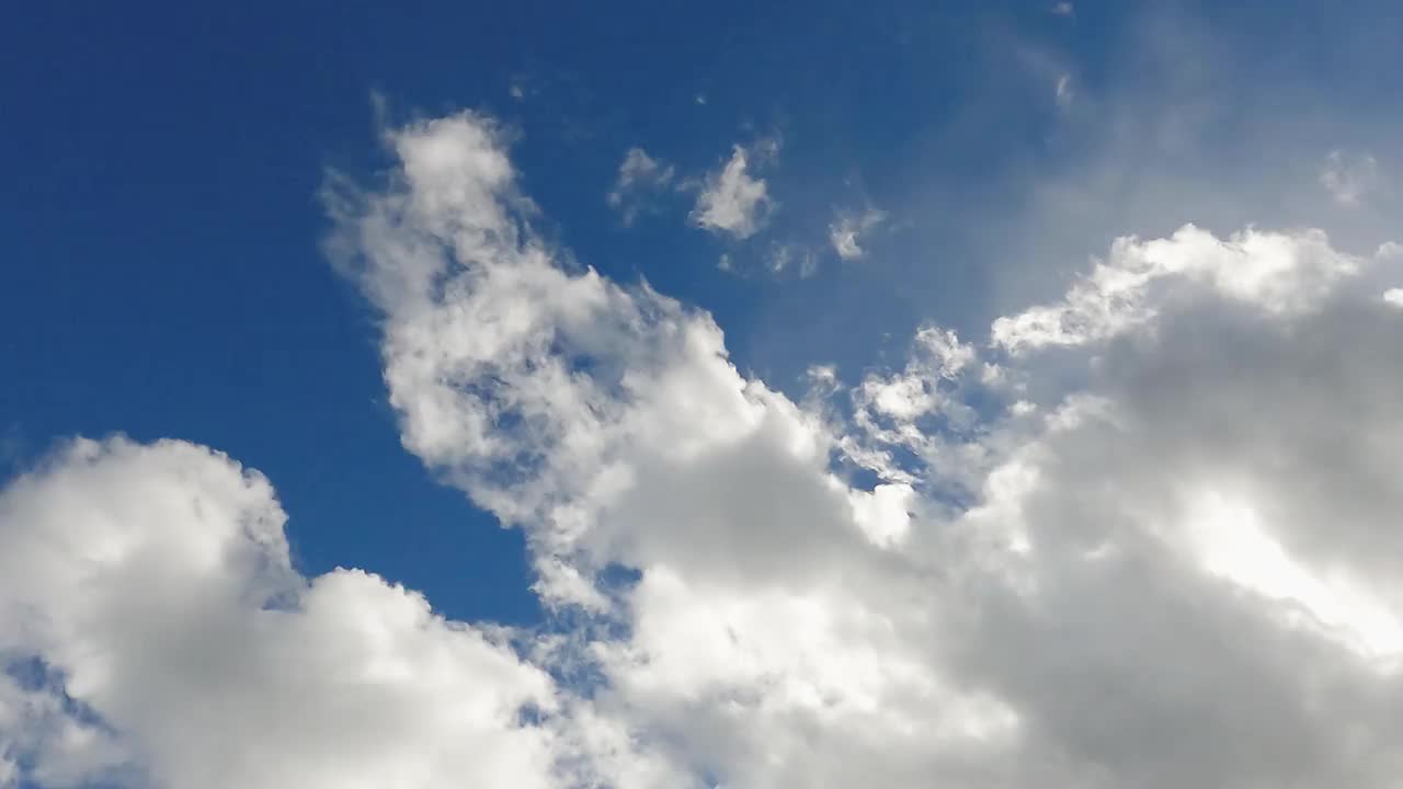 缕缕蓬松的白云在清澈的蓝天中飘过。夏天多云的一天云。Cloudscape自然背景4k分辨率的镜头。天堂和高空气。阳光透过云层照耀。有风的日子视频素材