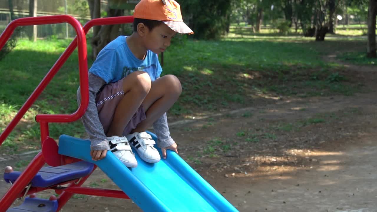 亚洲男孩在操场上玩滑块。视频素材