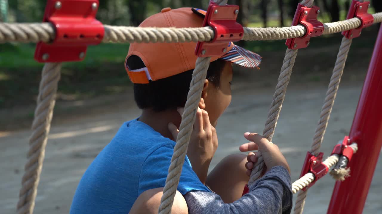 亚洲男孩在操场上爬网。视频素材