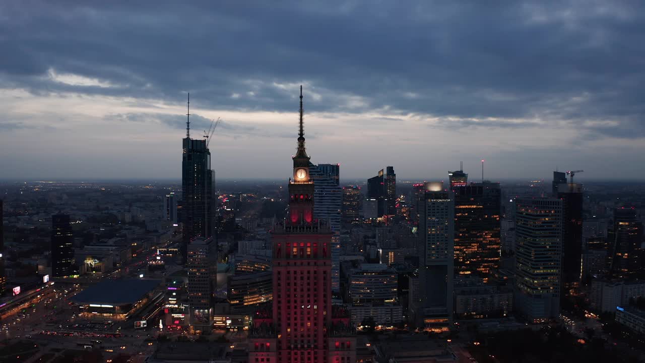 在夜晚的城市上空向后飞翔。黄昏时市区高层建筑的空中全景。波兰华沙视频素材