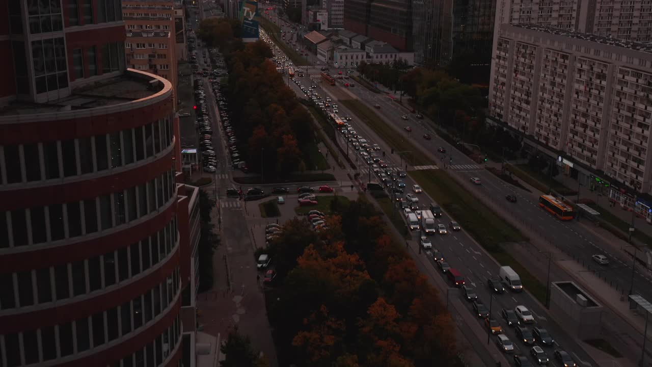 在宽阔繁忙的街道上空飞翔。向上倾斜，市中心的摩天大楼映衬着五彩缤纷的日落天空。波兰华沙视频素材