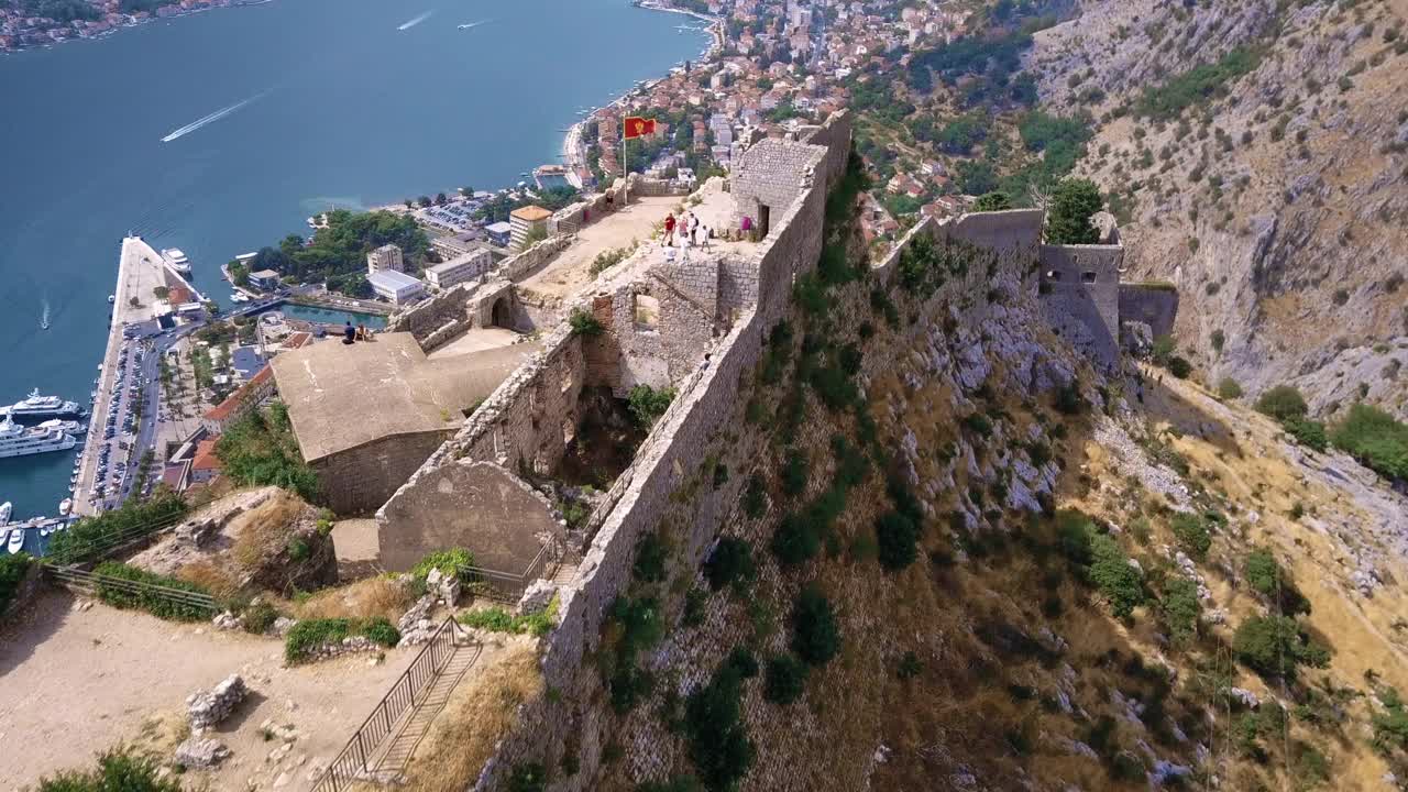 无人机俯瞰科托尔古城废墟，黑山国旗在风中飘扬视频素材