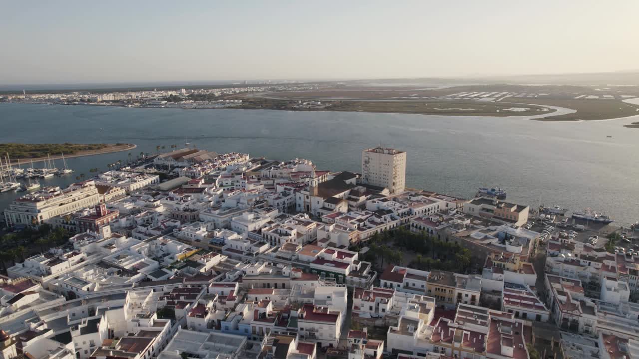 西班牙，Ayamonte:在海边传统的白色建筑上方的轨道上拍摄。鸟瞰中世纪城市和现代码头视频素材