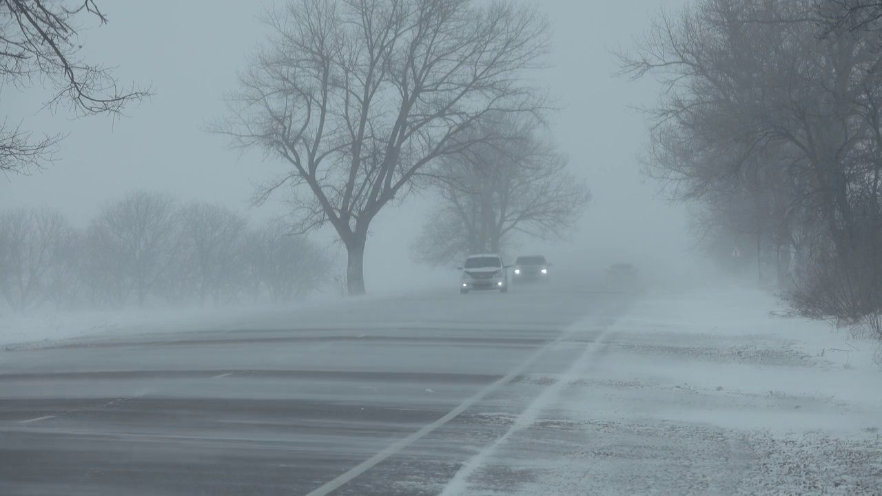 暴风雪中行驶在冬季道路上的汽车视频素材