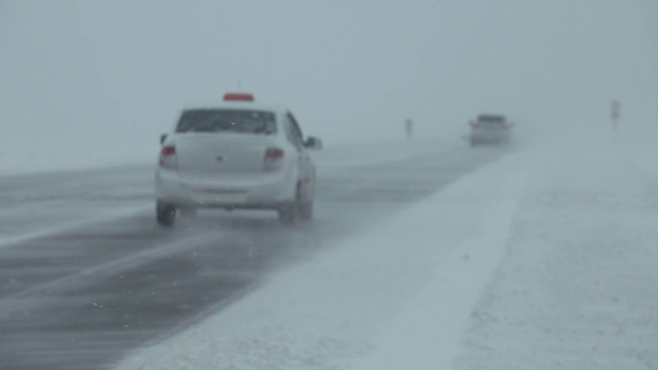 暴风雪中行驶在冬季道路上的汽车视频素材