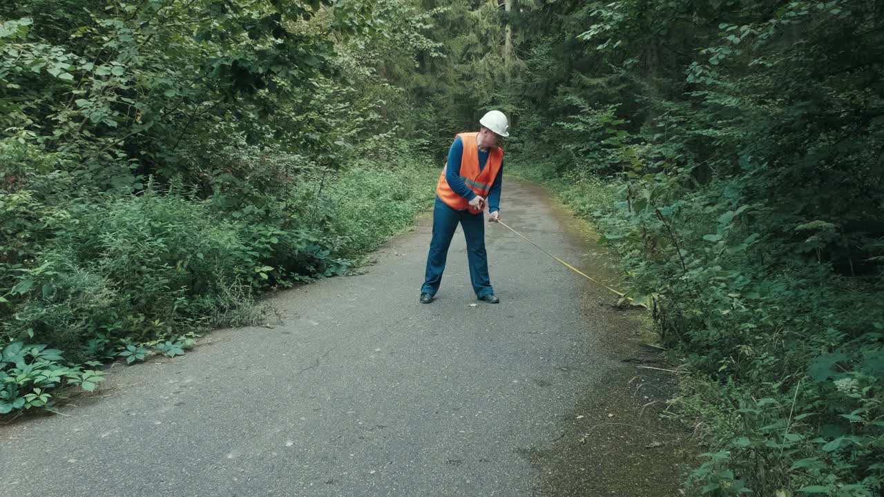 在森林中工作的工人在公路上用卷尺测量道路视频素材