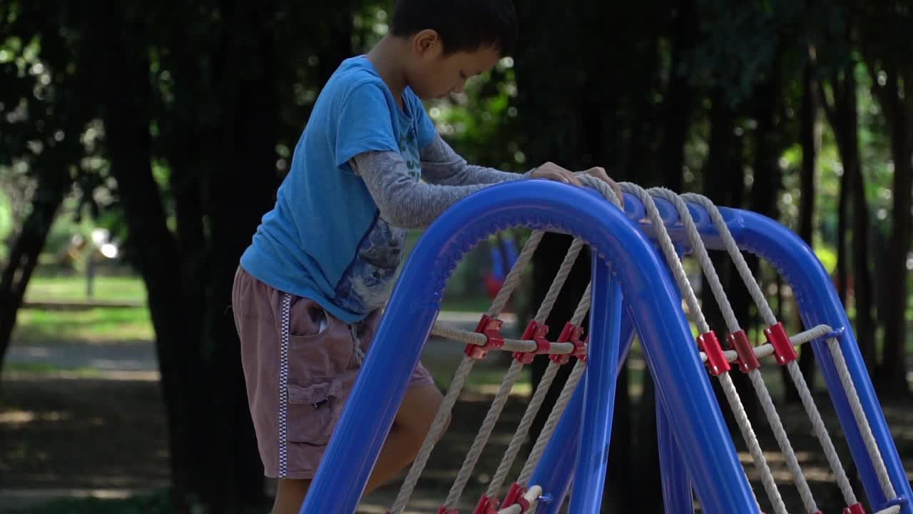 亚洲男孩在操场上爬网。视频素材