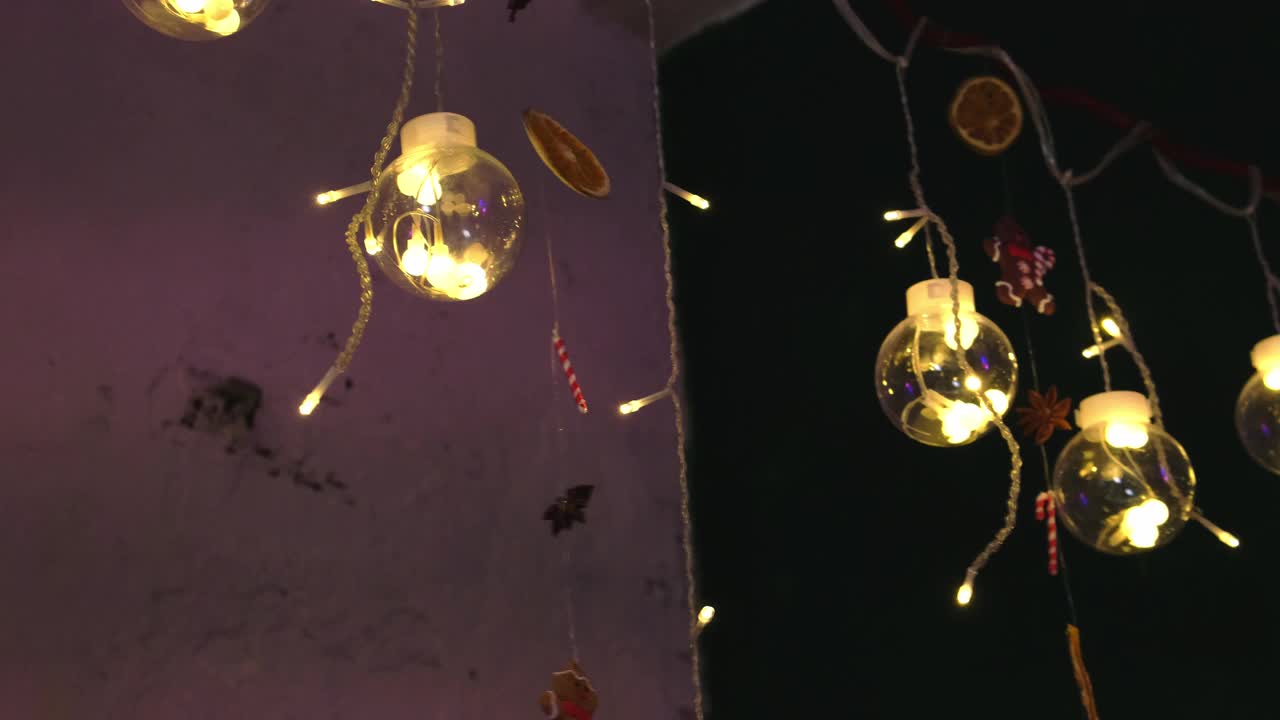 一个美丽的创意玻璃球花环内燃烧的灯泡在黑暗的背景。缓慢的运动。视频素材