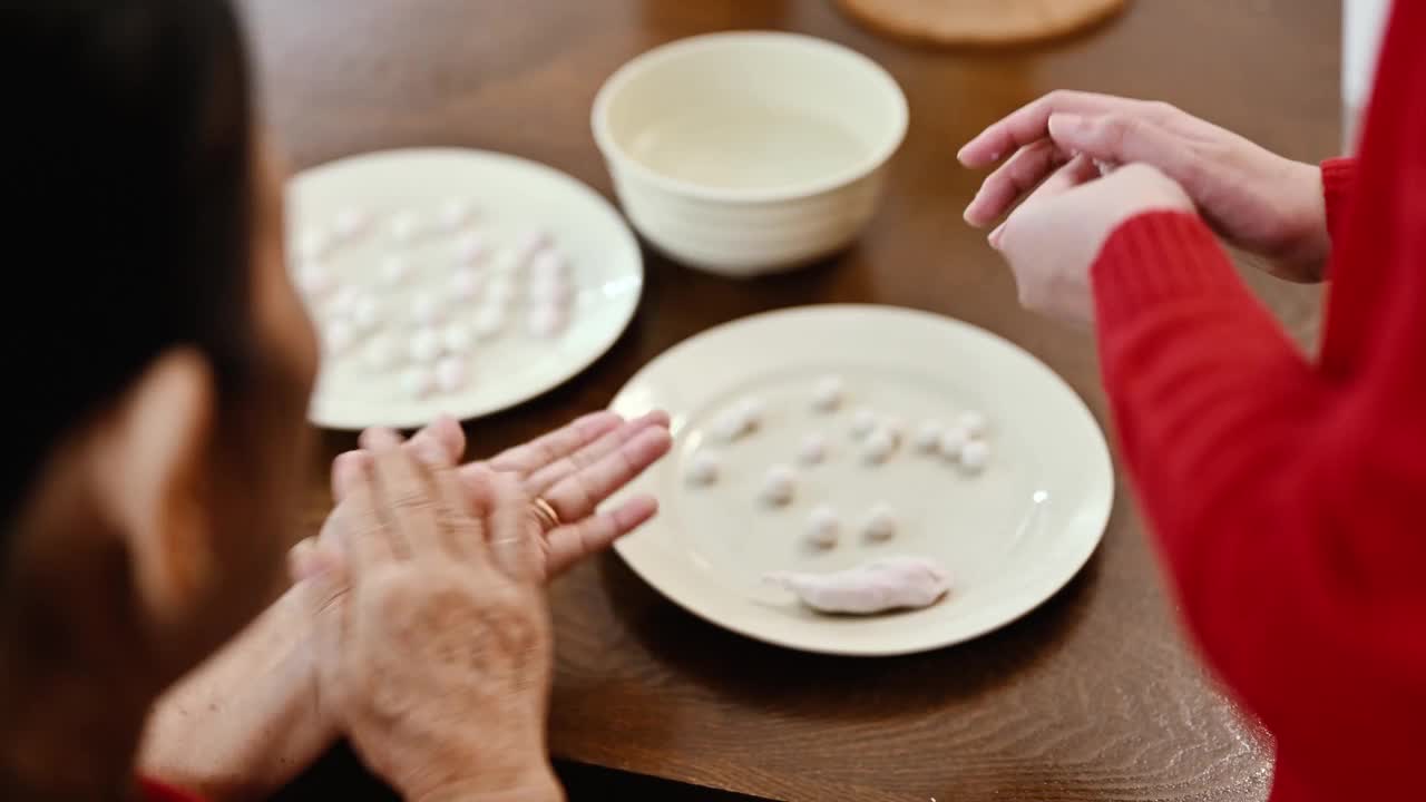 一位亚洲的祖母和她的孙女准备制作汤圆庆祝中国新年视频素材