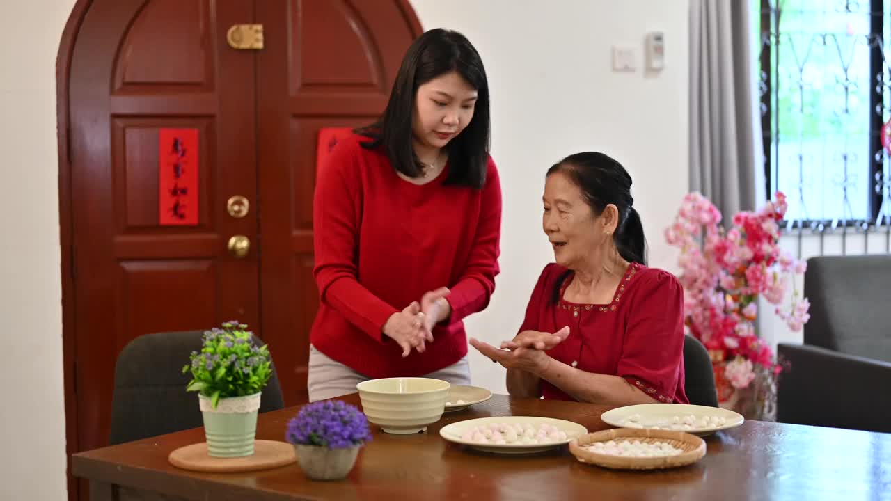 一位亚洲的奶奶和她的孙女正在为庆祝中国新年而准备汤圆视频素材