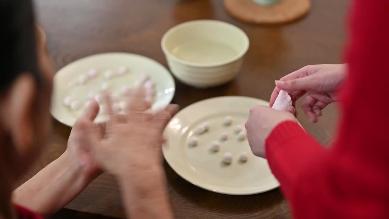 一位亚洲的奶奶和她的孙女正在为庆祝中国新年而准备汤圆视频素材