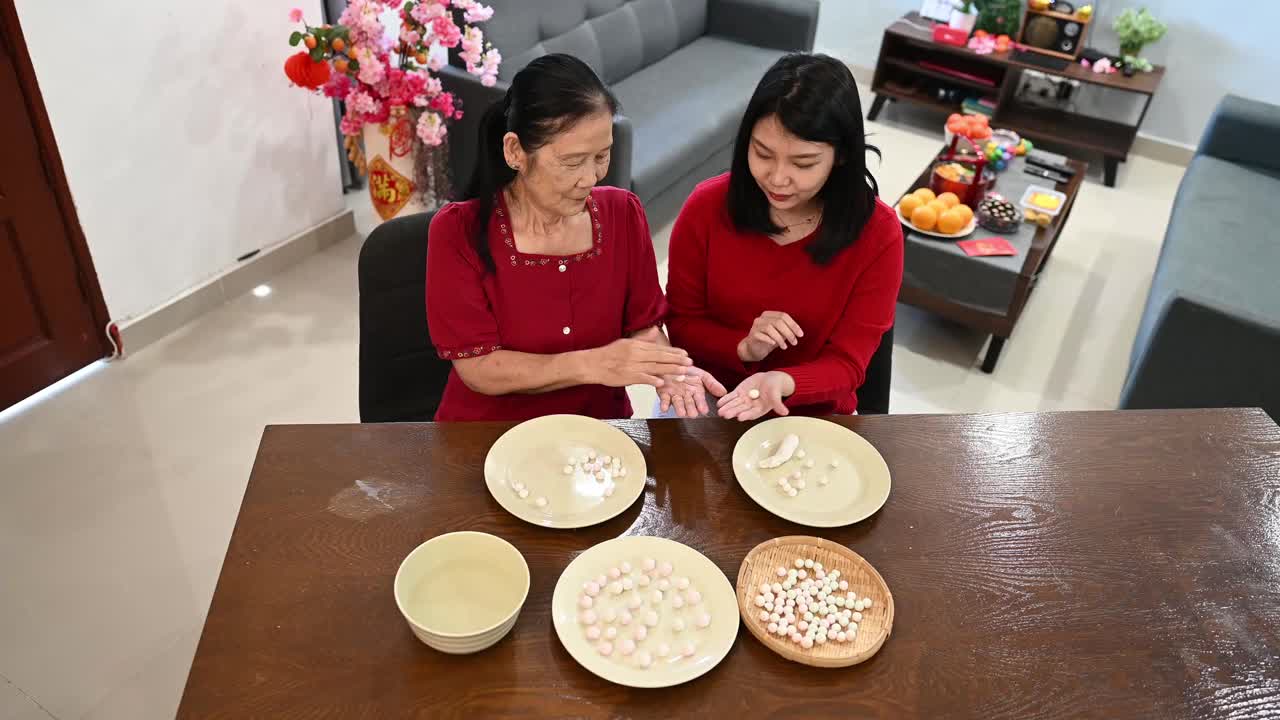 一位亚洲的奶奶和她的孙女正在为庆祝中国新年而准备汤圆视频素材