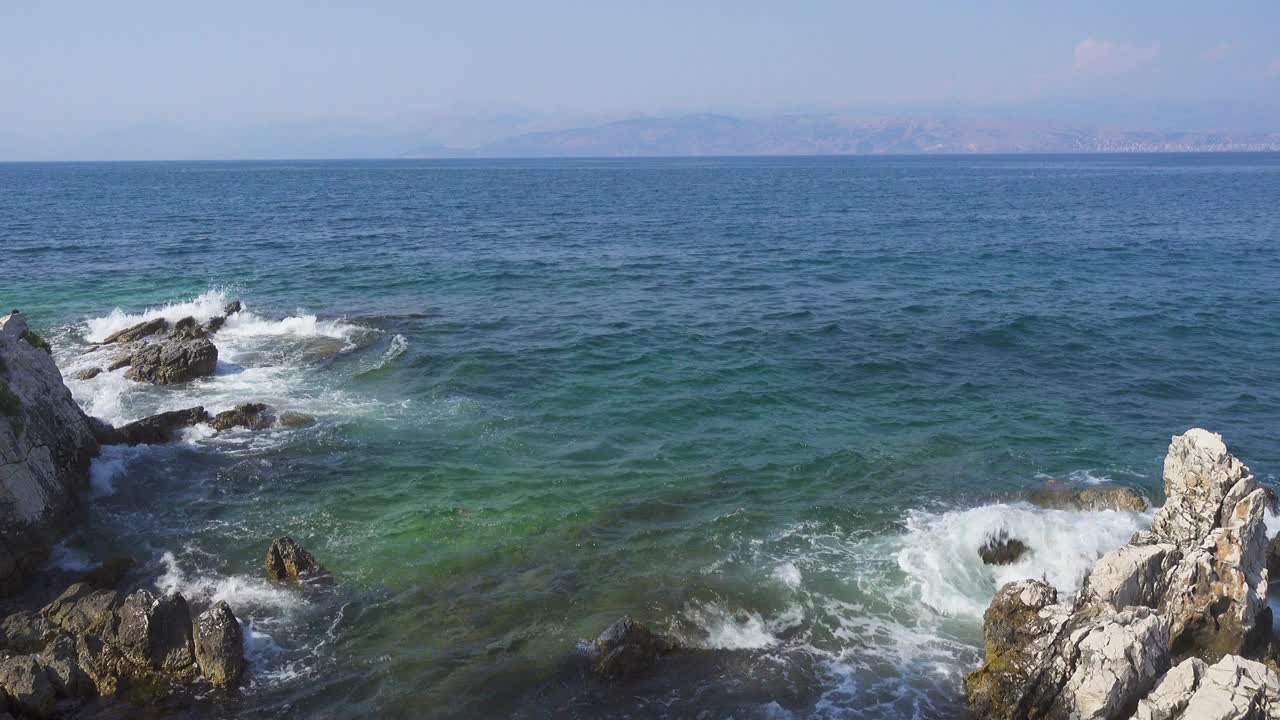 希腊岛屿的岩石海岸，平静的蓝色海面上波涛汹涌视频素材