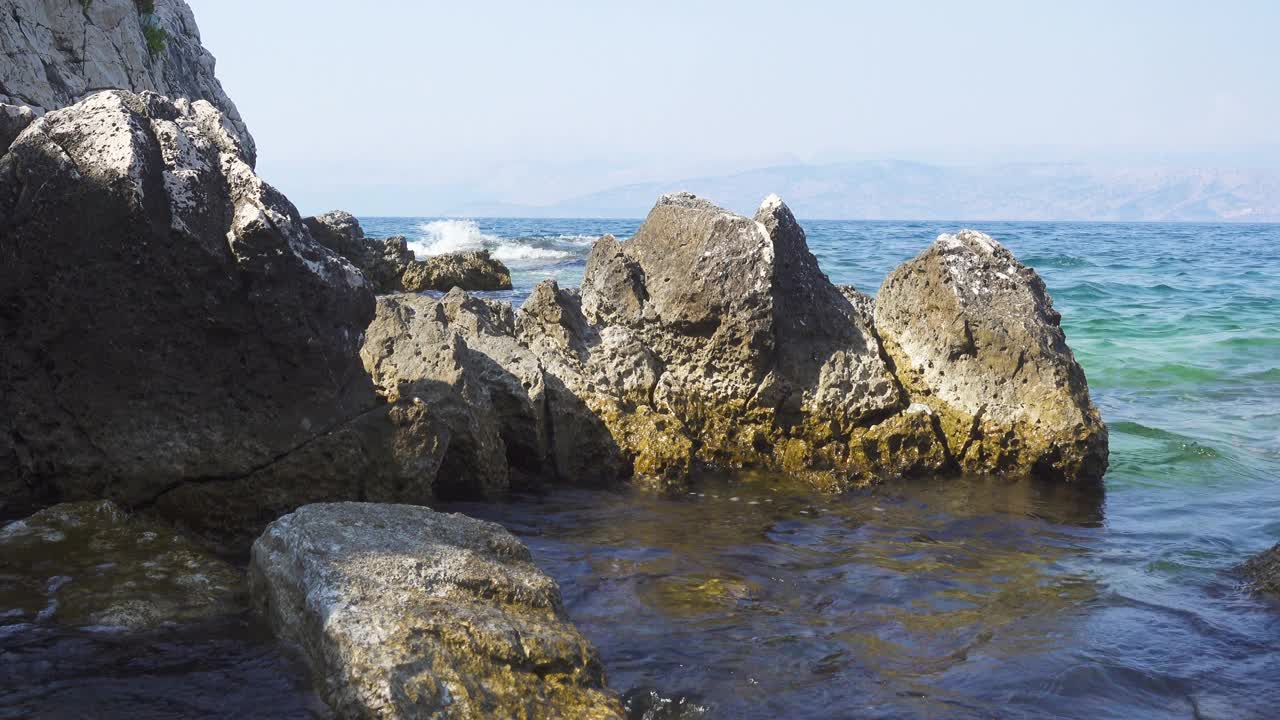 希腊岛屿的岩石海岸，平静的蓝色海面上波涛汹涌视频素材