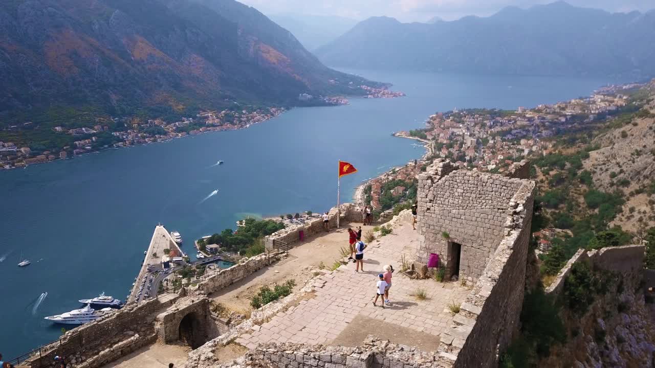 鸟瞰科托尔古城废墟，黑山国旗在风中飘扬视频素材