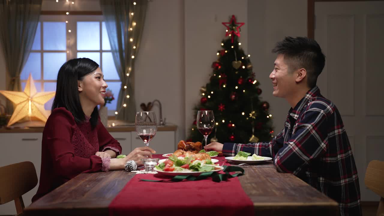 亚洲夫妻在餐桌上畅谈，在家里度过温馨的圣诞夜，一起庆祝节日视频素材